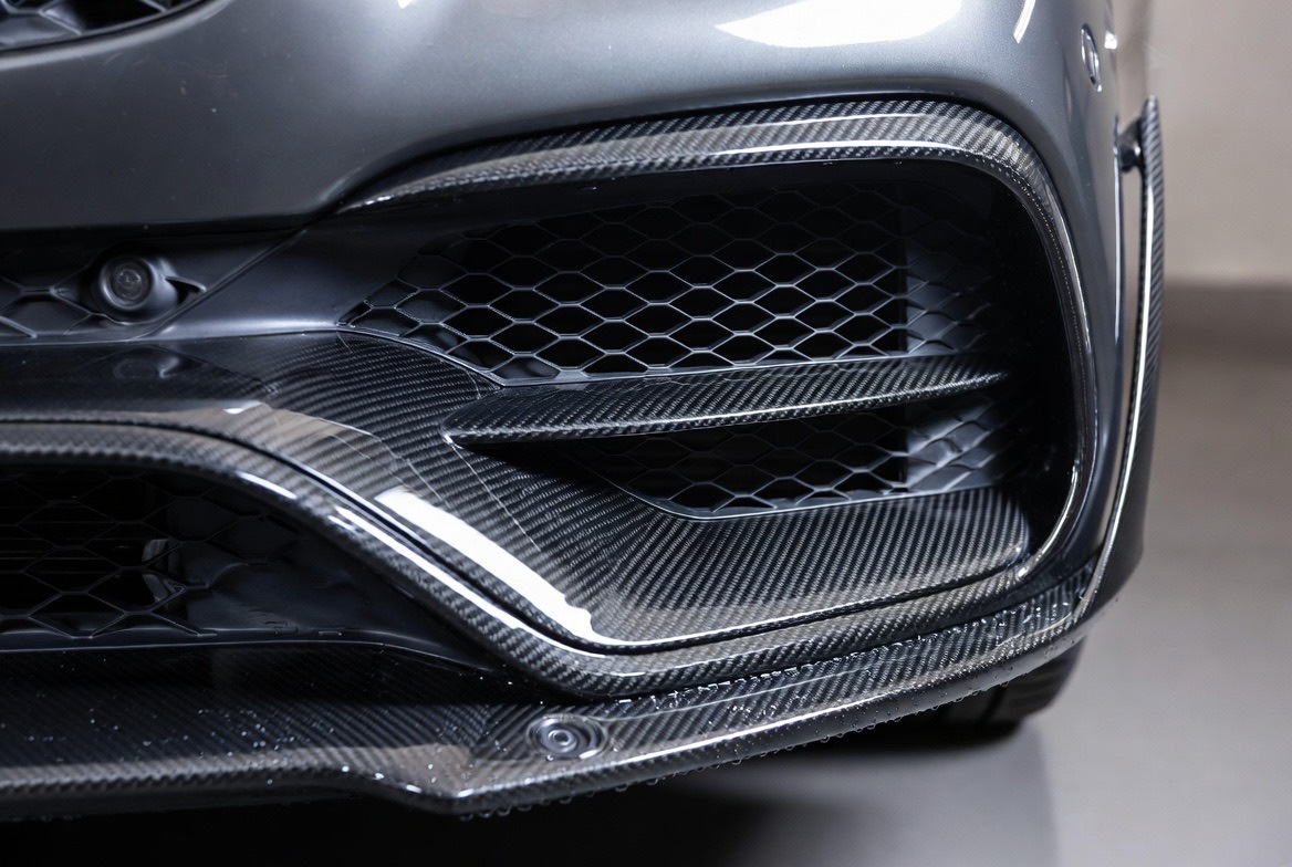 Крупный план карбонового бампера Mercedes AMG с воздухозаборниками и парктрониками